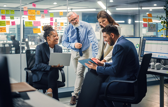In Modern Office: Diverse Team of Managers Use Laptop and Tablet Computers at a Company Meeting Discussing Business Projects. Young, Motivated and Experienced Employees Brainstorm in Conference Room.