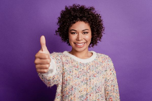 Happy young smiling african woman raise thumb up isolated on purple background
